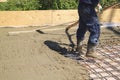 worker leveling fresh concrete slab with a special working tool