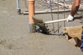 worker leveling fresh concrete slab with a special working tool