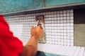 Worker leveling mosaic ceramic pattern tiles on bathroom shower area