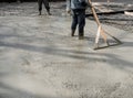 Worker leveling with wooden trowel the fresh poured concrete or cement at construction site Royalty Free Stock Photo