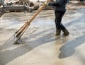 Worker leveling with wooden trowel the fresh poured concrete or cement at construction site Royalty Free Stock Photo