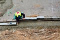 Worker levels the concrete bedding with a trowel for curbs installation. String line alignment. Royalty Free Stock Photo