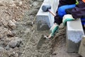 Worker levels and prepares the concrete bedding for the curbs using a trowel. String line is stretched for alignment.