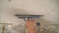 Construction notched trowel and worker hands with white mortar on wall. Worker levels a wall with mortar Royalty Free Stock Photo