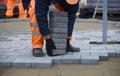 A worker lifts a concrete paving slab.