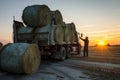 worker loading hay bales onto truck at sunrise Royalty Free Stock Photo