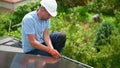 Worker looking on evenness of solar modules while building photovoltaic solar system on roof.