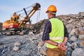 Worker looks on excavator works at opencast