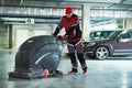 Worker with machine cleaning floor in parking garage. Royalty Free Stock Photo