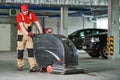 Worker with machine cleaning floor in parking garage.