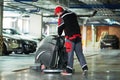 Worker with machine cleaning floor in parking garage.