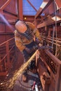 Worker maintenance using a silver G-clamp device holding metal workpiece, wearing a glove hand protection