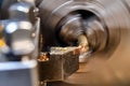 A worker makes a brass and bronze bolt on a lathe