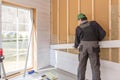 The worker makes finishing works of walls with a white wooden board, using laser line level. Building heat-insulating Royalty Free Stock Photo