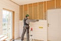 The worker makes finishing works of walls with a white wooden board, using laser line level. Building heat-insulating Royalty Free Stock Photo