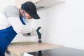 A worker makes a hole for installing a kitchen faucet in the countertop