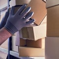 A worker man hands hold cardboard boxes on the shelves of a fully stocked warehouse. Warehouse overflowing with boxes of goods and Royalty Free Stock Photo