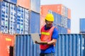 Worker man in hardhat and safety vest holding laptop, Foreman control loading containers box from cargo Royalty Free Stock Photo