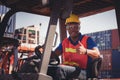 Worker man in hardhat and safety vest sitting in container stackers smiling with giving thumbs up as sign of Success Royalty Free Stock Photo