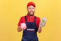 Worker man holding pos payment terminal and piggy bank, cashback, using paypass for service payment.