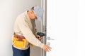 Worker man installs plastic windows white lock and seal adjustment. Royalty Free Stock Photo