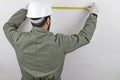 Man wearing worker uniform and hardhat trying the meter and taking measurements standing backwards Royalty Free Stock Photo