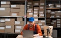 Worker manager checking on merchandise, working on laptop computer in warehouse facility Royalty Free Stock Photo