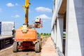 Worker is managing an elevated cherry picker at building site