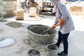 Worker manually mix cement powder, sand, stones in basin for mixing cement