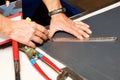 A worker marks out a sheet of roofing iron with a pencil and a metal ruler. Close-up of a worker`s hands Royalty Free Stock Photo