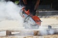 A worker mason cuts a curb with a circular saw when building a parking lot for tourist buses.