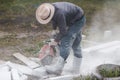 Worker mason cuts the sidewalk tile with circular saw while repairing sidewalk in city street