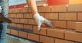 Worker or mason hands laying bricks close up. Bricklayer works at brick row. Brickwork on construction site Royalty Free Stock Photo