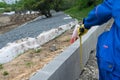 The worker measures the curb with a tape measure during the construction of pedestrian paths on the shore of a reservoir