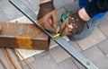 A worker measures metal at a construction site.