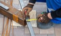 A worker measures metal at a construction site.