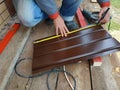 The worker measures the roulette with a metal sheet for installation on the roof