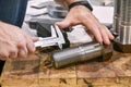 The worker measures the thread pitch on the bolt with a vernier caliper, after turning. Quality control department