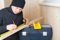 Worker, measures a wooden bar with a tape measure, a simple pencil Royalty Free Stock Photo