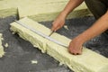 Worker measuring and cutting insulation material indoors, closeup