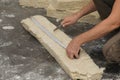 Worker measuring and cutting insulation material indoors, closeup