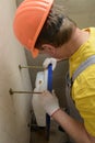 The worker is mounting a built-in toilet tank