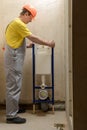 The worker is mounting a built-in toilet tank