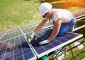 Worker mounting solar panels outside roof`s carcass.