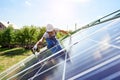 Worker mounting solar panels for renewable energy on house`s roof.