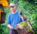 A worker moves a large log to a chain for splitting in a machine.