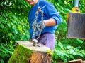 A worker moves a large log to a chain for splitting in a machine.