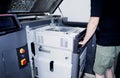 Worker moves working camera of 3D printer into 3D printer. Industrial 3D printer