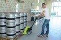 Worker moving barrels with pallet truck