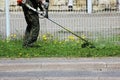 Worker mowing grass with a trimming machine. Royalty Free Stock Photo